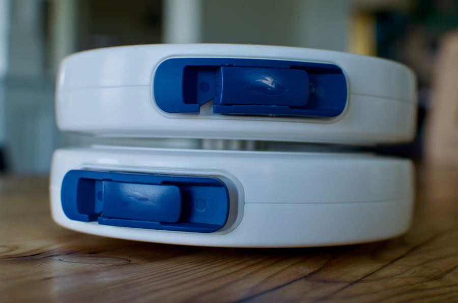 Two LINEGUARD units stacked one on top of the other on a wooden table, photographed edge-on so both navy release latches line up — the two units included in the Twin Pack.